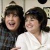 Two people in close proximity, one in a blue plaid shirt and the other in a white top, both wearing headbands with decorative elements.