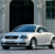 Static pixel art of a light blue sedan parked in front of a dark garage door with a window to the right, rendered in low-resolution 8-bit style.