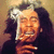 Pixelated image of a person with long dark hair holding a glass of beer, smiling broadly against a warm-toned background.