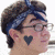 Pixelated profile of a person with dark hair, glasses, and a heart-shaped mark on the cheek.