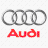 Four interlocking silver rings above red text reading 'Audi' on a white background with faint gray grid pattern.