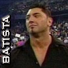 Static image of a person in a dark shirt with a V-neck, standing against a blurred background with text reading 'BATTISTA' vertically on the left.