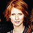 Pixelated image of a person with reddish-brown hair, light skin tone, and red lips against dark background.