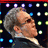 Pixelated image of a person with gray hair and dark clothing against a dark background with colored dots, next to a red rectangle with white text.