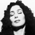 Black-and-white pixelated image of a person with long dark hair, closed eyes, and a neutral mouth expression against a plain background.
