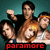 Pixelated image of four people in a group pose with one person raising their fist, set against a teal background and red text at the bottom.