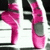 Two pink, stylized, cartoonish figures with rounded shapes and dark accents stand side-by-side against a black-and-white striped background.