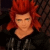 Pixelated image of a person with bright red hair styled upward, closed eyes, and dark clothing against a dark background.