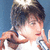 Pixelated close-up of a person with dark hair holding an object near their face against a blue background.