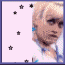 Pixelated image of a person with short blonde hair and blue earrings, surrounded by black stars on light purple background.
