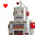A silver robot with red accents and a small antenna stands against a white background, its head slightly tilted as a red heart icon moves across the frame.