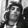 Black-and-white static image of a person with long wavy hair wearing a headband and dark clothing, partially cropped on the right side.