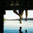 Animated sequence showing silhouetted figures jumping on a beach with ocean and sky background, transitioning to a close-up of hands holding a golden object.