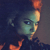 Pixelated image of a character with greenish skin, blue eyes, and orange hair, set against a dark background with orange accents.