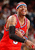 Pixelated image of a person in red athletic wear with blue accents, wearing a headband and holding a black object near the chest.