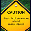 Yellow diamond-shaped caution sign with black border and blue dot at top, displaying text about heart broken avenue ahead many injured.