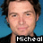 Pixelated portrait of a person with brown hair against blue background, wearing dark clothing and displaying text "Micheal" at bottom.