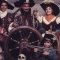 A child in a pirate costume with a black tricorn hat featuring white skull-and-crossbones, holding a sword and standing near a ship's wheel.
