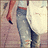Pixelated static image of a figure in blue jeans and red top against light background with pinkish tones.