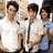Three people stand together in a group, two wearing white shirts and one in light blue with yellow accents.