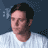 Pixelated static image of a person's head and shoulders in profile view against a dark blue background with light gray pixel clusters.