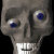 Animated sequence of a gray skull with blue eyes and white teeth, showing mouth opening/closing and cheek bulge movement against black background.