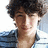 Pixelated portrait of a person with curly dark hair wearing a blue and white striped shirt, next to teal text reading 'nick jonas + jess santos' on white background.
