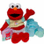 Pixelated red muppet character with orange nose, black eyes, and open mouth wearing light blue cape over beige shirt and red pants.
