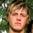 Pixelated close-up of a person with light brown hair and closed eyes against a green foliage background.
