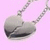 A silver heart-shaped pendant on a chain against a pink background, with one frame showing purple text over the heart.