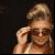 A black background displays pink text with a small photo of a person adjusting sunglasses in the top-left corner.