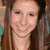 A pixelated close-up of a person with long brown hair, light skin tone, and visible facial features including eyes, nose, mouth, and neck.