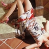 A person in a patterned dress and pink high heels lies on a tiled floor with legs raised, viewed from above.