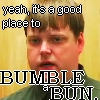 Static image of a person with short brown hair against a yellow background, overlaid with pixelated text reading "yeah, it's a good place to BUMBLE BUN.".