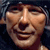 Pixelated close-up of a human face with exaggerated features and a wide grin, rendered in low-resolution 256x256 pixels on a dark background.