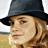 A 48x48 pixel animated contact sheet showing three sampled frames of a woman with long wavy blonde hair wearing a black fedora hat in outdoor settings, displayed as a 2x2 grid with one empty cell.