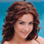 A static pixelated image shows a person with brown wavy hair against a solid blue background, wearing a light-colored top with visible shoulder straps.