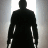 Silhouette of a figure in dark clothing with white accents on arms and hands against a light gradient background.