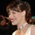 Pixelated profile view of a person with short brown hair wearing a light-colored sleeveless top against a dark background.