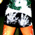 A pixelated figure in green and white top, black shorts, and orange legs, with a visible hand gesture and partial torso.