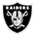 Black and white pixelated shield-shaped icon featuring a skull with crossed bones, topped by a row of small square shapes resembling teeth or studs.
