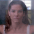 A pixelated close-up of a person with long dark hair wearing a light-colored sleeveless top against a blurred background with blue and white tones.