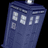 Pixelated blue police box with white and a circular top against black background, next to blue with pixelated text