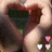 Two hands form a heart shape with fingers, surrounded by small pink and white hearts on grassy background.