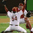 Animated sequence showing baseball players in white uniforms with red helmets and numbers, a person in red hoodie and beanie, and a 'CHAMPIONS' logo.