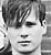 Black-and-white pixelated image of a person's face on the left and text reading "*Tom* Delonge" on the right against a dark background.