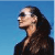 Pixelated profile view of a person with long dark hair against a blue gradient background, wearing a dark top.