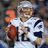 Pixelated image of a football player in white uniform holding a brown ball, with blue and gray background sections containing text.