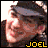 Pixelated static icon featuring a person with light skin tone, brown hair, and a gray headband, with yellow text reading "JOEL" at the bottom right corner.