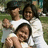Three people in white shirts pose outdoors on grass, with one person holding a child; the image appears to be part of an animated sequence.